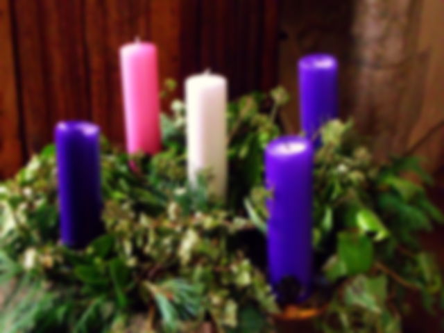 five candles, a white one in the centre, and surrounded by a christmas wreath