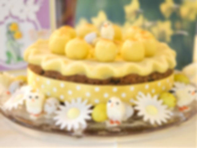 A cake decorated with a yellow ribbon, balls of marzipan and little flurry chick ornaments