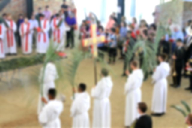 Top down view of a church service. Clergy holding palm leaves and a cross.