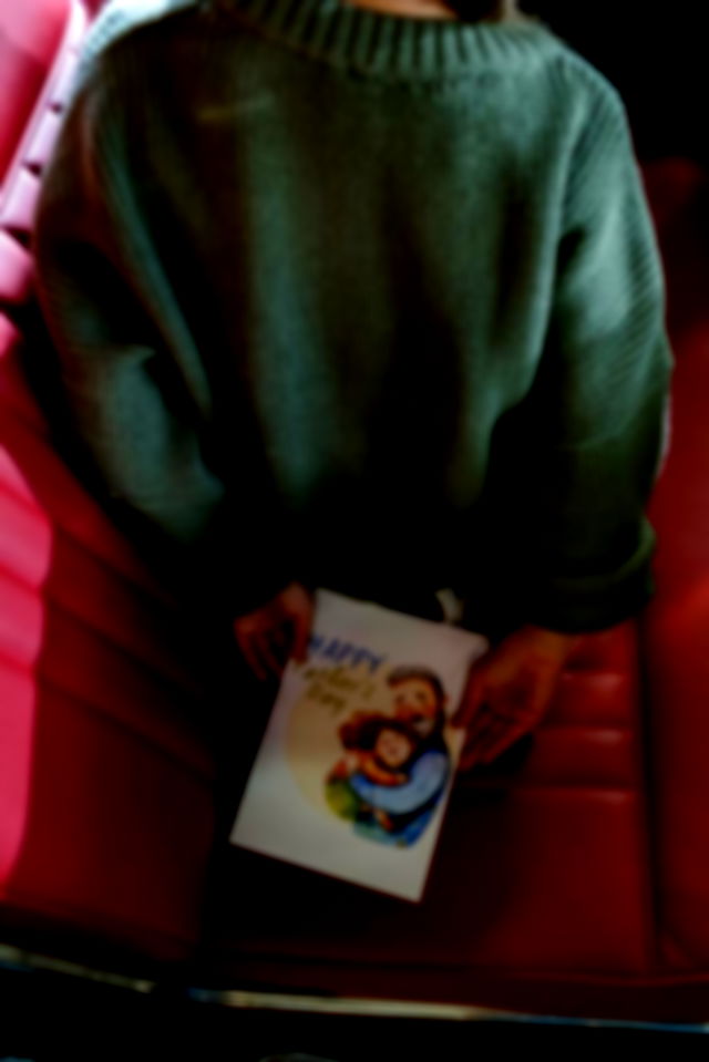 A Child Holding a Surprise Greeting Card for her Dad