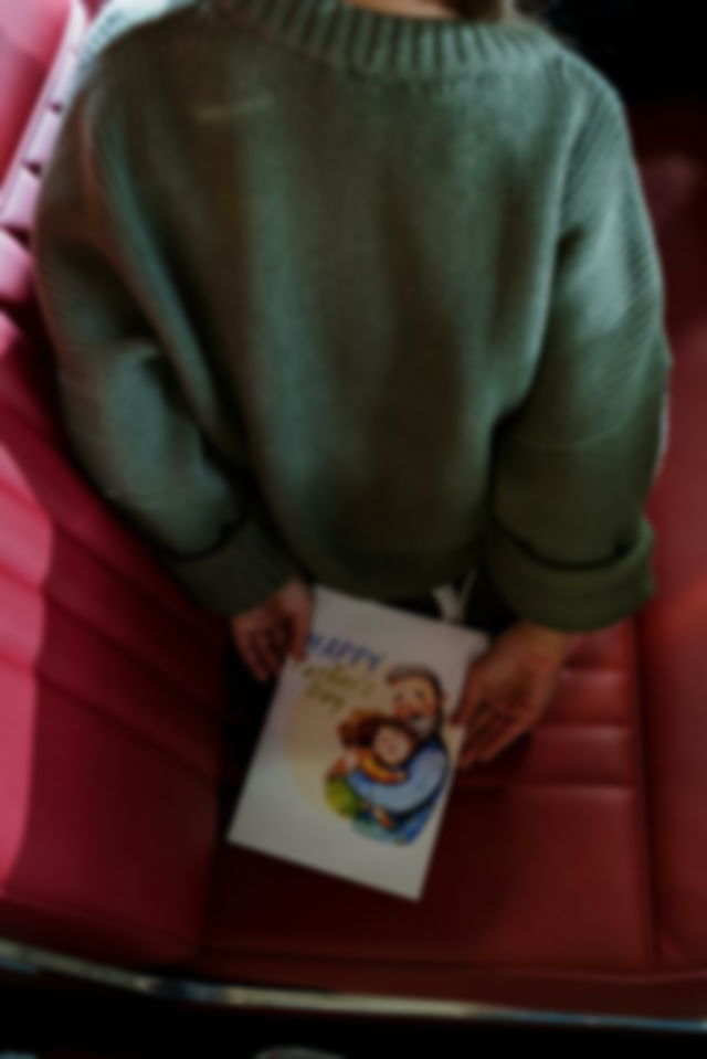 A Child Holding a Surprise Greeting Card for her Dad