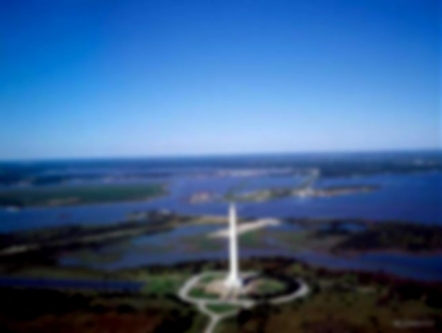 An aerial photo of the monument, blue sky and river behind it