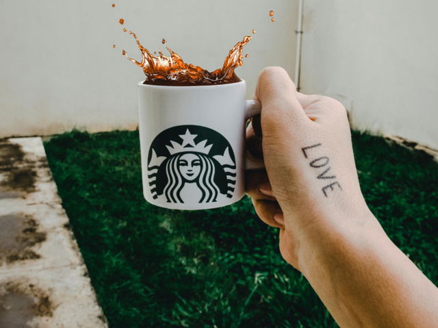A hand holding starbucks coffee