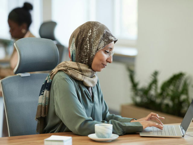 A hijabi woman working on laptop