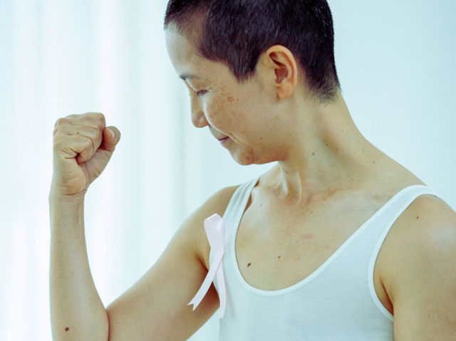 Asian woman in top with ribbon as symbol of Breast Cancer day