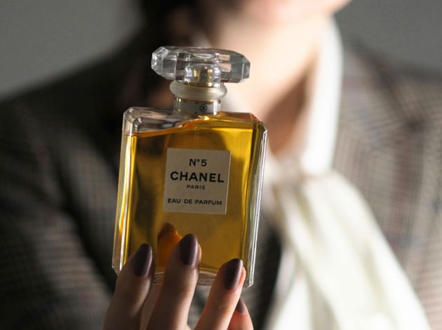 A woman holding a Chanel perfume