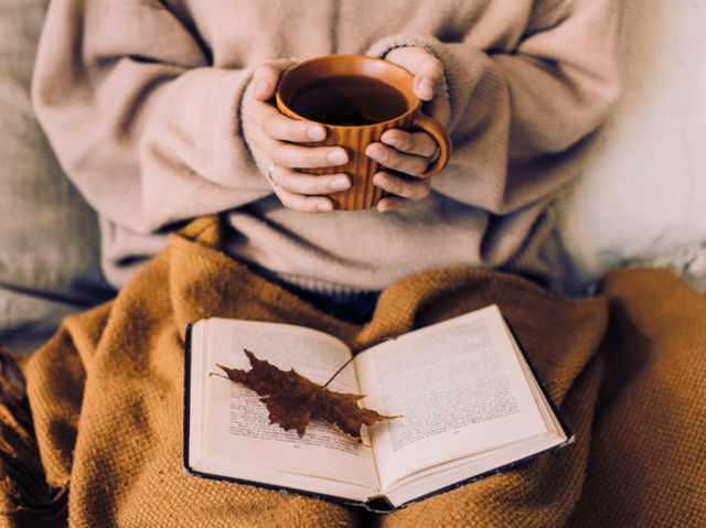 A woman holding a cup of coffee and a book