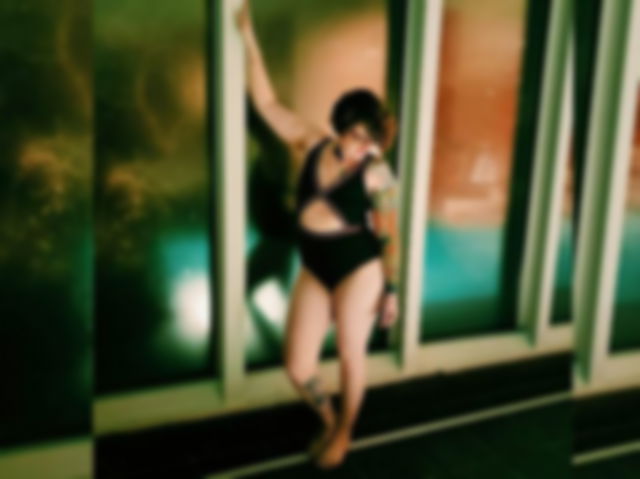 Woman in Swimsuit Posing next to Indoor Swimming Pool at Night