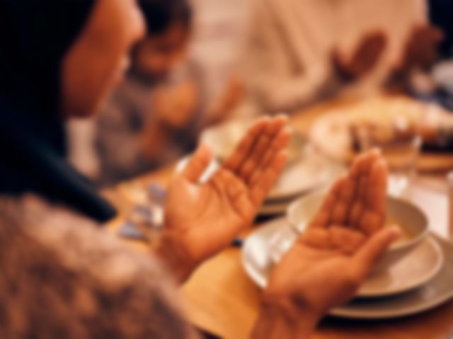 A muslim woman praying at the dinner table