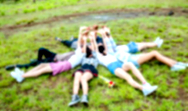 Cousins form a circle while lying on the grass while hands on top