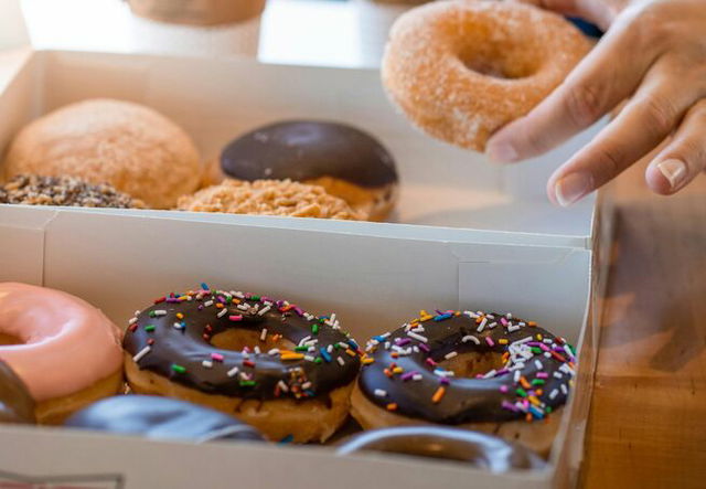 Close-up of a Person Taking a Donut Out of a Box