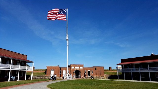 The american flag flying above Fort McHenry on a bright blue cloudless day