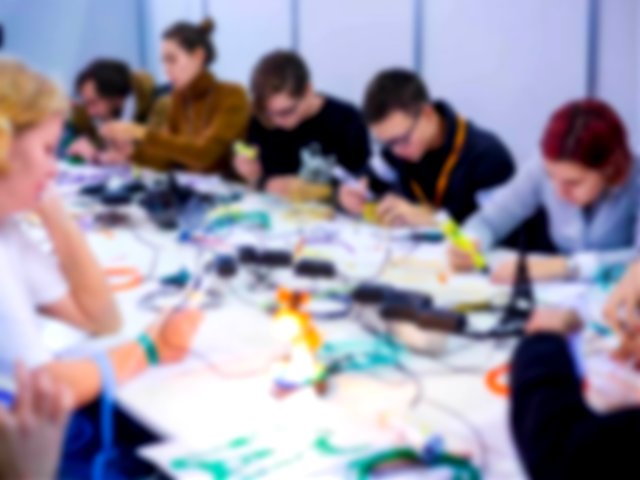 Group of people using 3D printing pens and making plastic models at a Science Exhibition