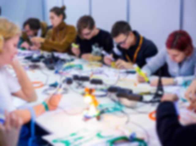 Group of people using 3D printing pens and making plastic models at a Science Exhibition