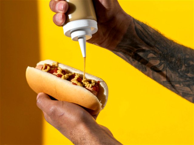 A man putting mustard sauce on a Hot Dog