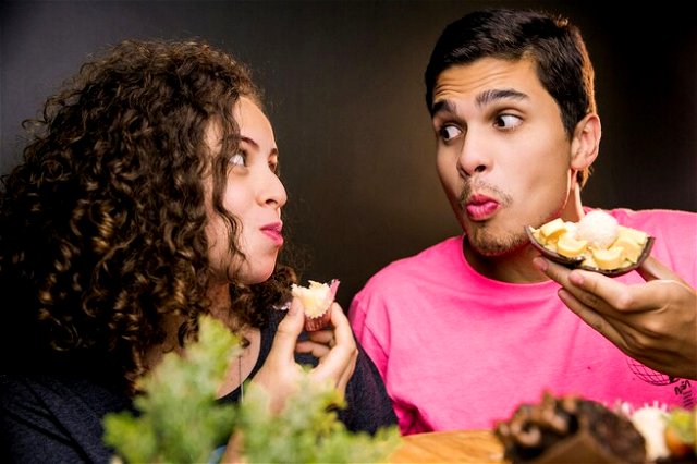 A man and woman look at each other while eating