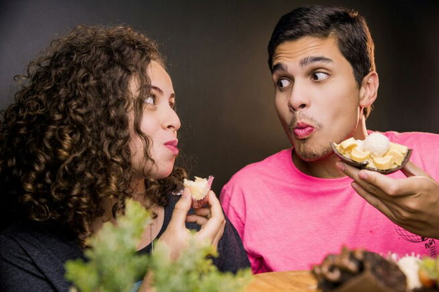 A man and woman look at each other while eating