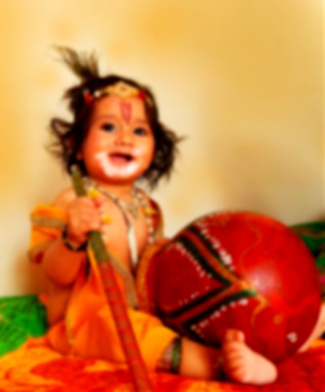 A baby dressed up as Bal Krishna reenacting Krishna‘s love for makhan and stealing it from the pot