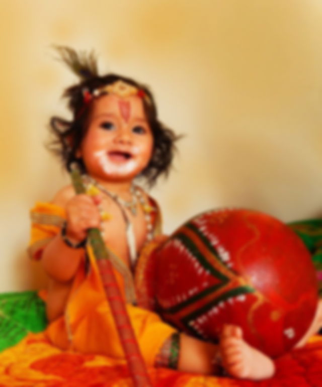 A baby dressed up as Bal Krishna reenacting Krishna‘s love for makhan and stealing it from the pot