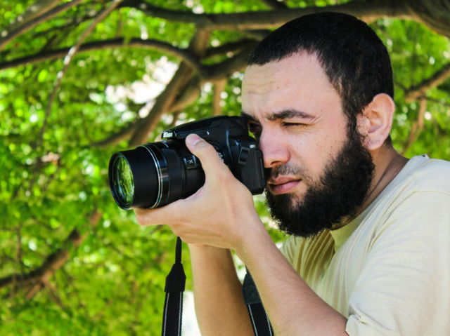 Man in beige shirt clicking photos