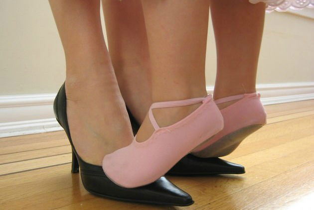 Menina de sapatilha dan&ccedil;ando em cima dos p&eacute;s da m&atilde;e