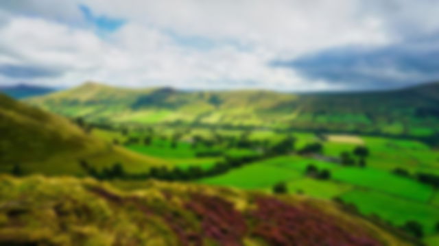 The lush green grass of the hope valley with a dramatic white and dark cloudy sky.