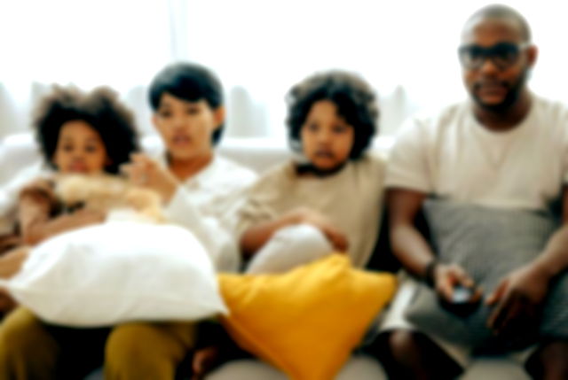 Multiethnic family watching TV with dog on sofa