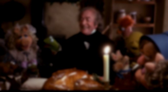 Scrooge surrounded by muppets, all laughing and sharing in Christmas dinner