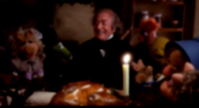 Scrooge surrounded by muppets, all laughing and sharing in Christmas dinner