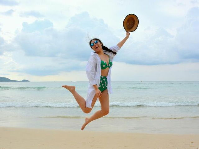 a girl wearing a bikini jumping on the beach