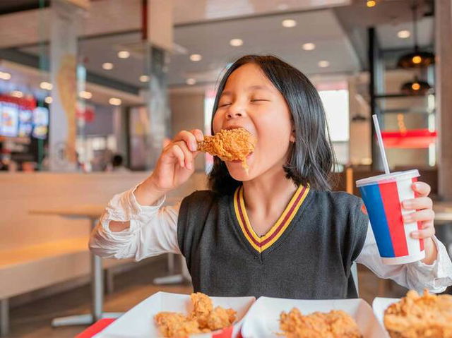 A kid eating fried chicken in a restaurant