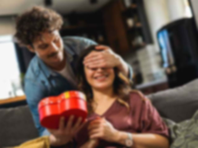 A man gifting something in a heart-shaped box to a woman