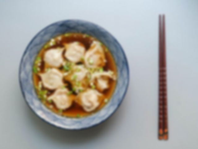 Round White and Blue Ceramic Bowl With Cooked Ball Soup and Brown Wooden Chopsticks