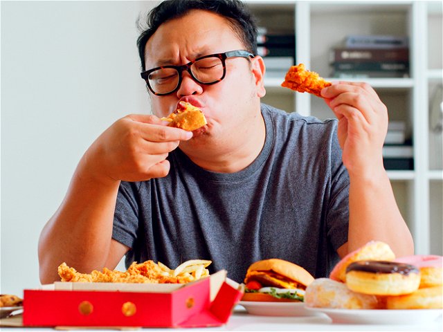 An asian man eating fast food