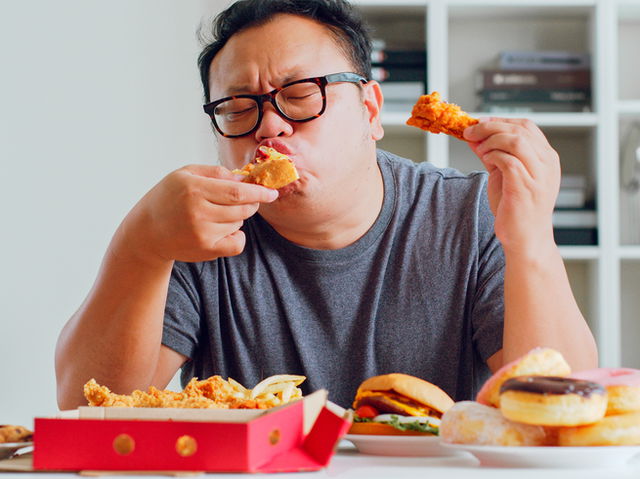 An asian man eating fast food