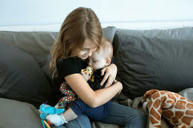 A girl hugging her baby sister