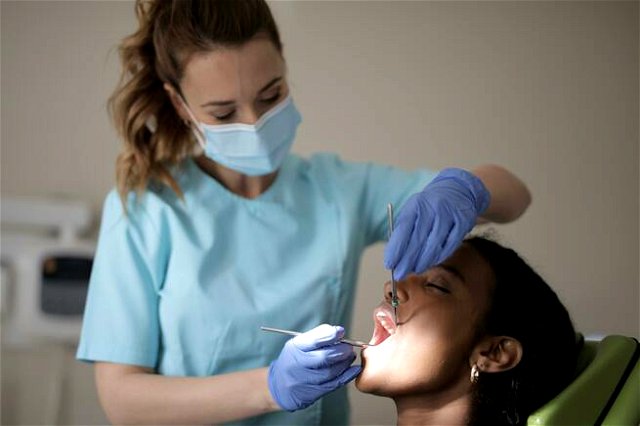 Young female dentist treating teeth of female patient in modern clinic