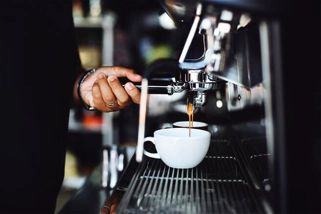 close up of hands operating a coffee machine