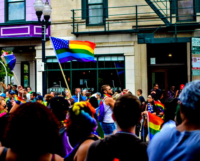 People Gathered Near Building Holding Pride Flag at Daytime