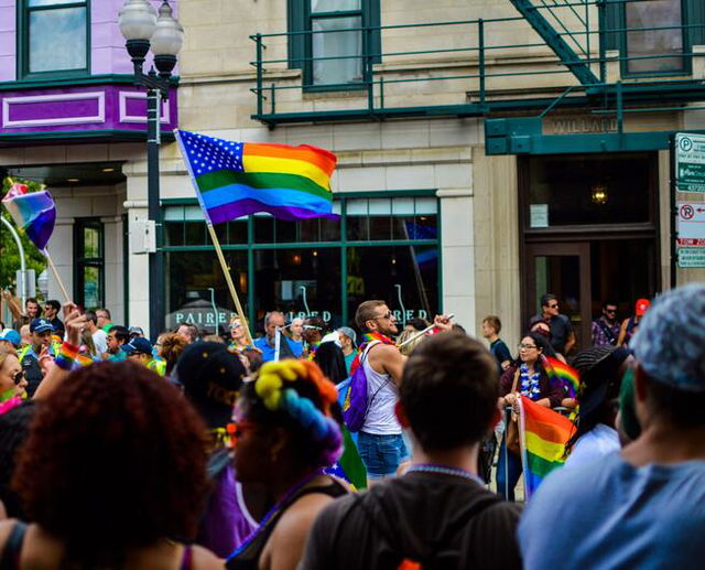 People Gathered Near Building Holding Pride Flag at Daytime