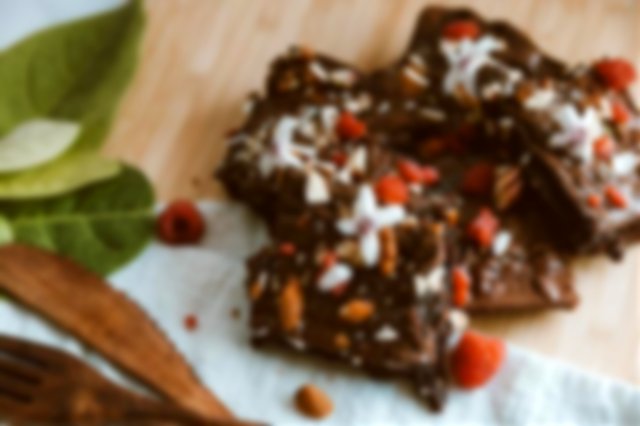a plate of chocolate brownies covered in berries and almonds