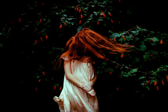 Girl With Red Hair in White Dress Standing in Front of Green Plants