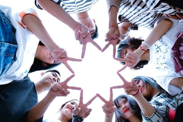An image of a group of kids using their fingers to form a star to symbolise friendship