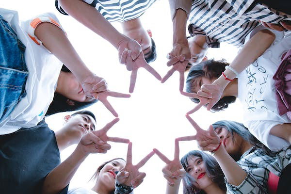 An image of a group of kids using their fingers to form a star to symbolise friendship