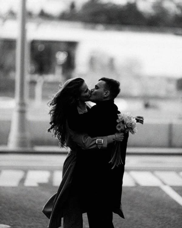 A black and white picture of a girl and a man kissing