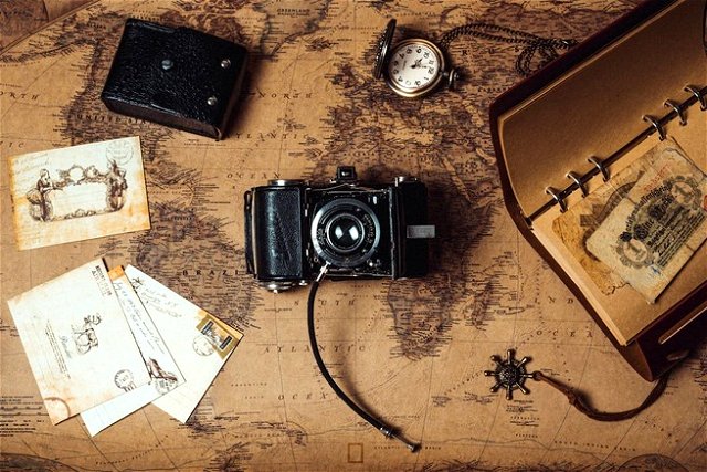 AN image of a film camera on a vintage map suroounded by photo and films
