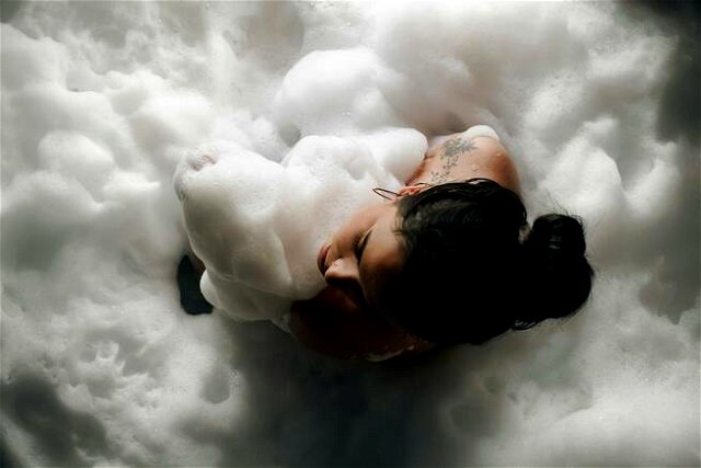 A woman laying in a bubble bath with foam