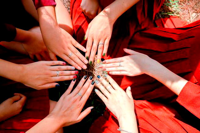 Ladies’ hands in the middle of a circle, finger nails decorated.