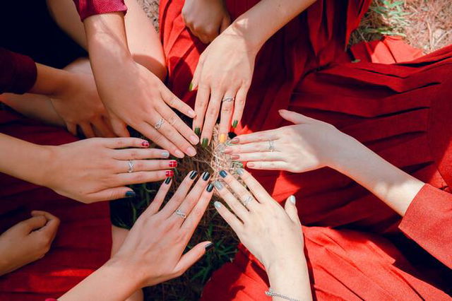 Ladies’ hands in the middle of a circle, finger nails decorated.