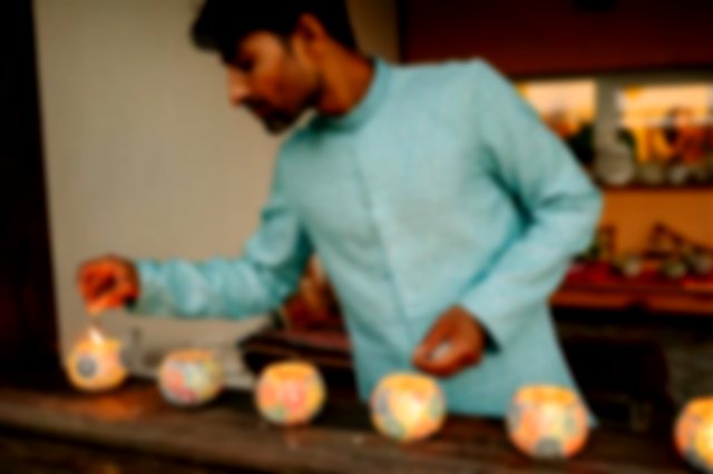 A man in a blue kurta lighting candles
